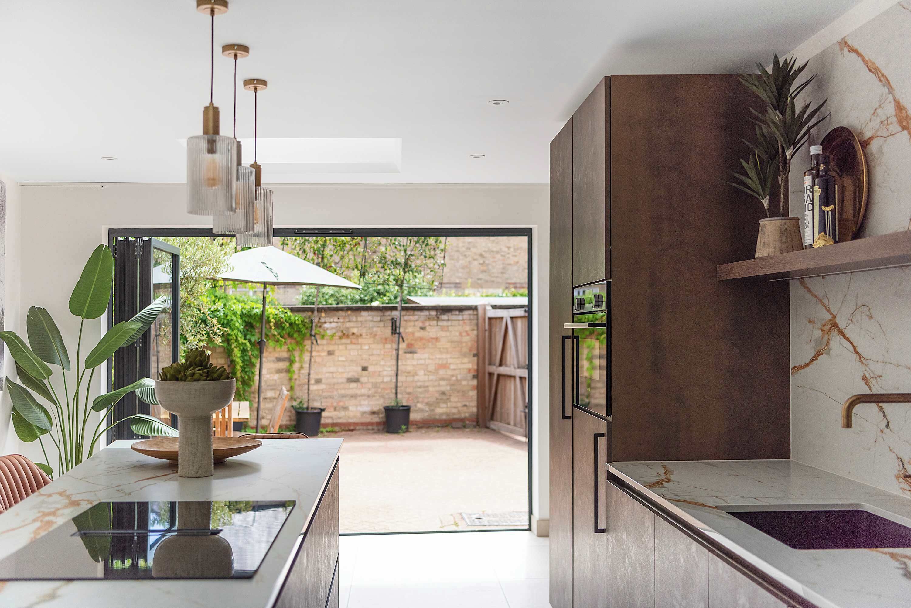 A modern kitchen with a marble countertop, a built-in oven, and a hanging light fixture.