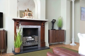 A living room with a fireplace, a television, and a potted plant. - Stylish 4BR Victorian Home Parking with EV Charger (Cambridgeshire)
