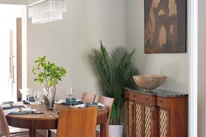 A dining area with a round table, chairs, a plant, a painting, and a decorative bowl. - Stylish 4BR Victorian Home Parking with EV Charger (Cambridgeshire)