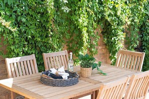 A wooden table with chairs, a woven basket, a bottle, and a potted plant. - Stylish 4BR Victorian Home Parking with EV Charger (Cambridgeshire)