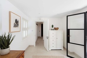 A hallway with a white cabinet, a framed picture on the wall, and a potted plant. - Stylish 4BR Victorian Home Parking with EV Charger (Cambridgeshire)