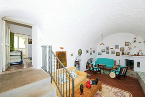 A spacious living area with a staircase, a sofa set, and a fireplace. - 8th-century dwelling near Positano (Nocelle)