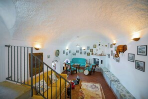 An interior with a staircase, a sofa set, a dining area, and wall-mounted artwork. - 8th-century dwelling near Positano (Nocelle)
