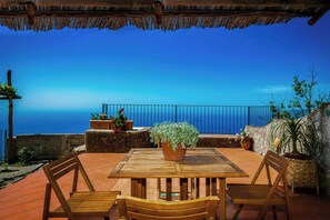 A wooden table with chairs, potted plants, and a view of the sea. - 8th-century dwelling near Positano (Nocelle)