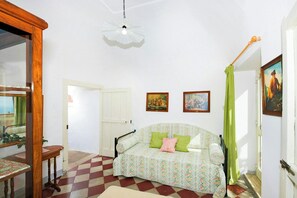 A room with a checkered floor, a floral sofa, a green curtain, and two framed pictures on the wall. - 8th-century dwelling near Positano (Nocelle)