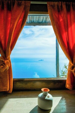 A window with curtains, a vase, and a view of the sea. - 8th-century dwelling near Positano (Nocelle)