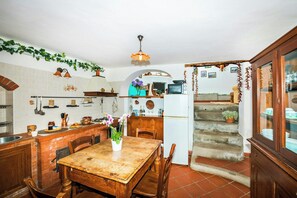 Una cocina con una mesa de madera, un refrigerador y diversos utensilios de cocina.