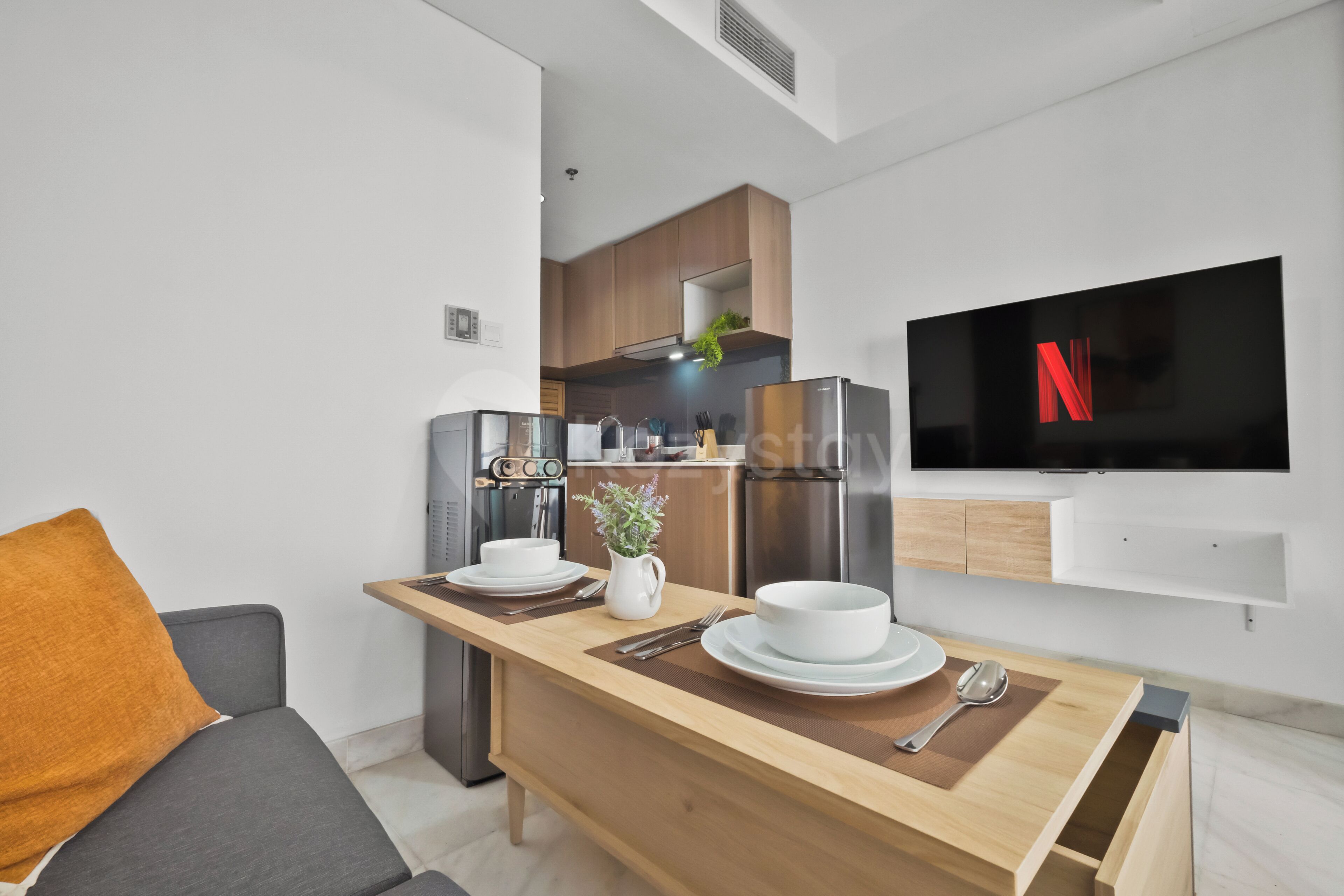 A modern kitchen with a built-in oven, refrigerator, and a flat-screen TV mounted on the wall.