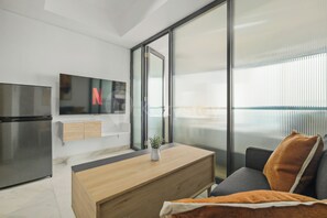 A modern kitchen with a built-in refrigerator, a wooden dining table, and a sofa with a cushion. - Jasen by Kozystay - Alam Sutera (Tangerang)