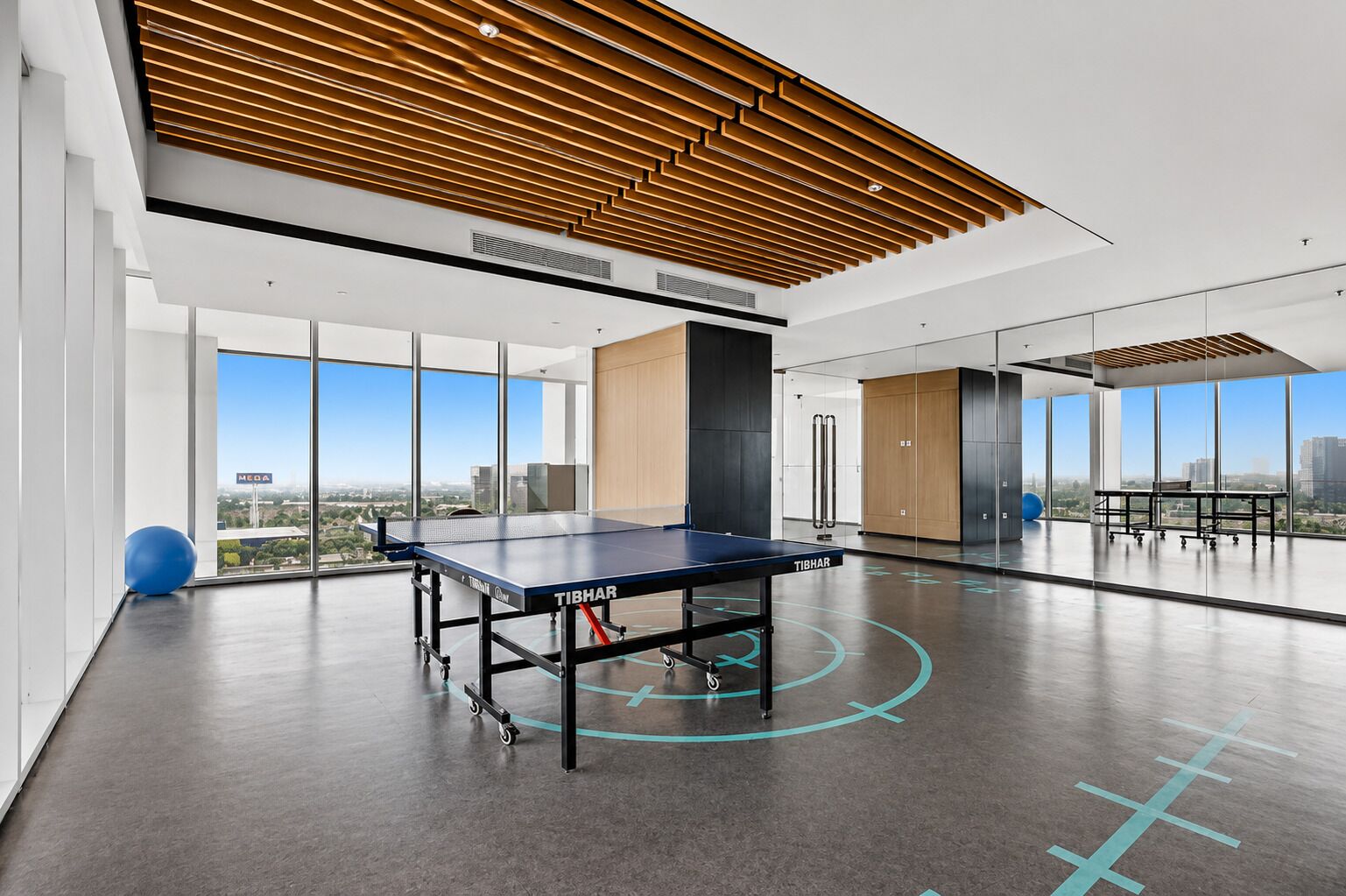 Un'ampia area interna con tavolo da ping pong, ampie finestre e vista sulla città.