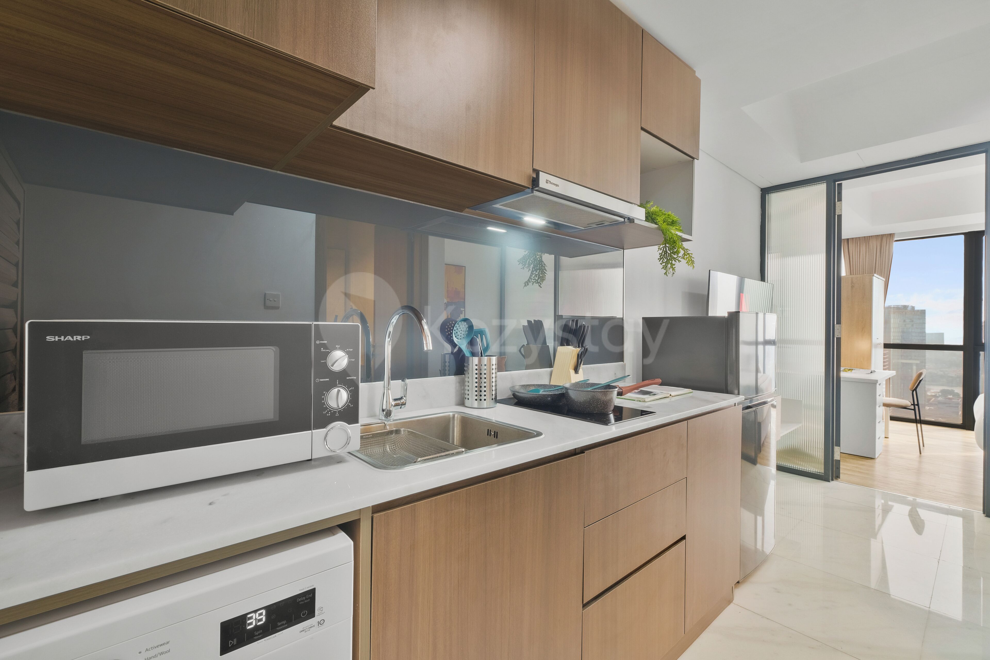 Una cocina moderna con microondas integrado, pileta de acero inoxidable y muebles de madera.