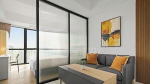A modern living room with a grey sofa, a wooden coffee table, and a cityscape painting on the wall. - Jasen by Kozystay - Alam Sutera (Tangerang)
