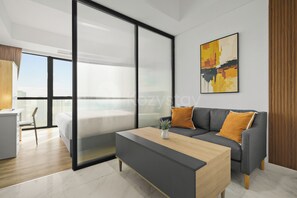 A modern living room with a grey sofa, a wooden coffee table, and a cityscape painting on the wall. - Jasen by Kozystay - Alam Sutera (Tangerang)
