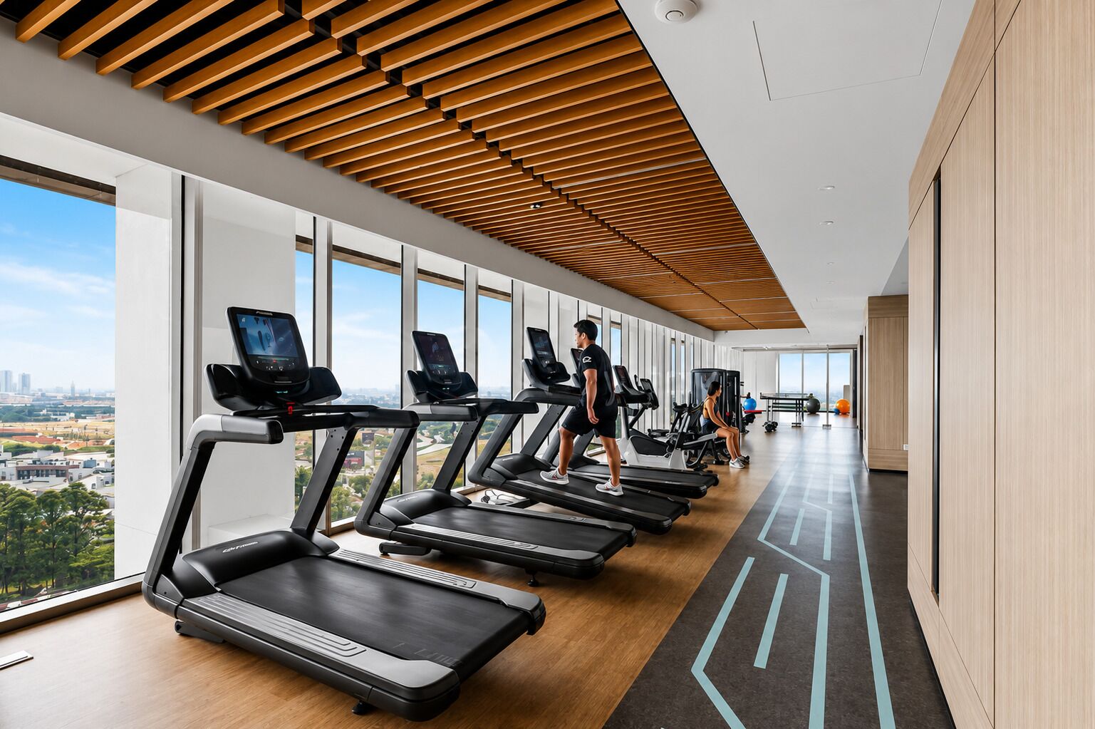 A gym with treadmills, exercise equipment, and large windows offering a city view.