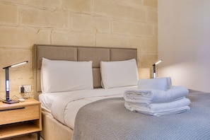 Une chambre d’hôtel avec un lit, deux lampes de chevet, une table de chevet et une serviette pliée posée sur le lit.