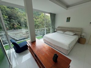 A bedroom with a large bed, a wooden desk, and a view of a garden through a sliding glass door. - Kamala Jungle Suite 80m² Balcony, 2 Pools, Gym & Sauna Fast Fiber WiFi (Kamala, Kathu)