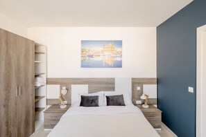 A bedroom with a bed, bedside tables, a wardrobe, and a cityscape painting on the wall.