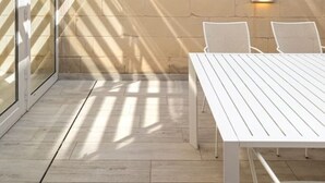 Un'area patio con tavolo e sedie, un muro con un punto luce e vista sul cielo.