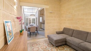 Un soggiorno con divano, una zona pranzo con tavolo e sedie, e una cucina sullo sfondo.