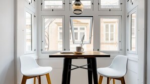 Ein Zimmer mit einem Tisch, zwei Stühlen, einem Laptop und einer Tasse.