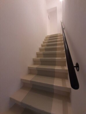 A staircase with a handrail, leading to a landing with a door.
