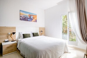 A hotel room with a bed, bedside tables, a lamp, a painting, and a window with curtains.