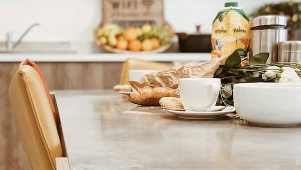 Een keukentafel met een koffiekop, een schaal, een fles en een bord eten.