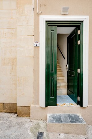 A building entrance with a green door, a white door, and a small step leading to a tiled floor. - MarsaxlokkRoom - Hammock Vibes Towns House (Tas-Sliema)
