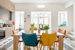 A modern kitchen with a dining area, featuring a large table, chairs, and a view of the outdoors.