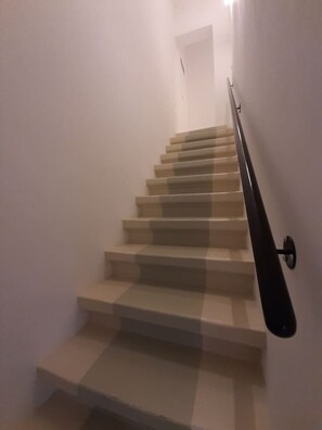 A staircase with a handrail on the right side, leading to a door at the top.