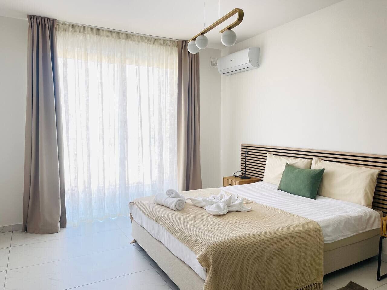 Une chambre d’hôtel avec un lit, des rideaux, un appareil de climatisation et une table de chevet.