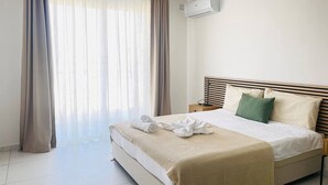 Una camera d'albergo con un letto, tende, un condizionatore d'aria e un comodino.