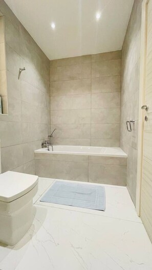 Moderni kylpyhuone, jossa on kylpyamme, wc ja suihku.