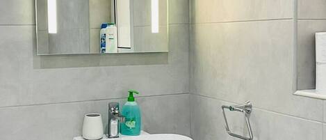 Une salle de bain avec un lavabo blanc, un miroir et un porte-serviettes.