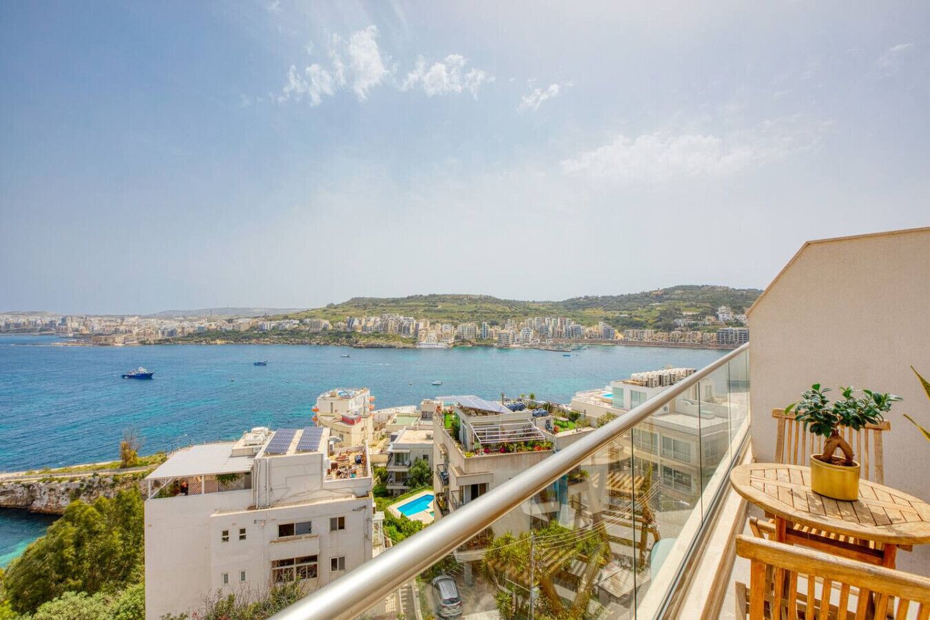 Uma varanda com vista para um horizonte costeiro, incluindo edifícios e uma massa de água.