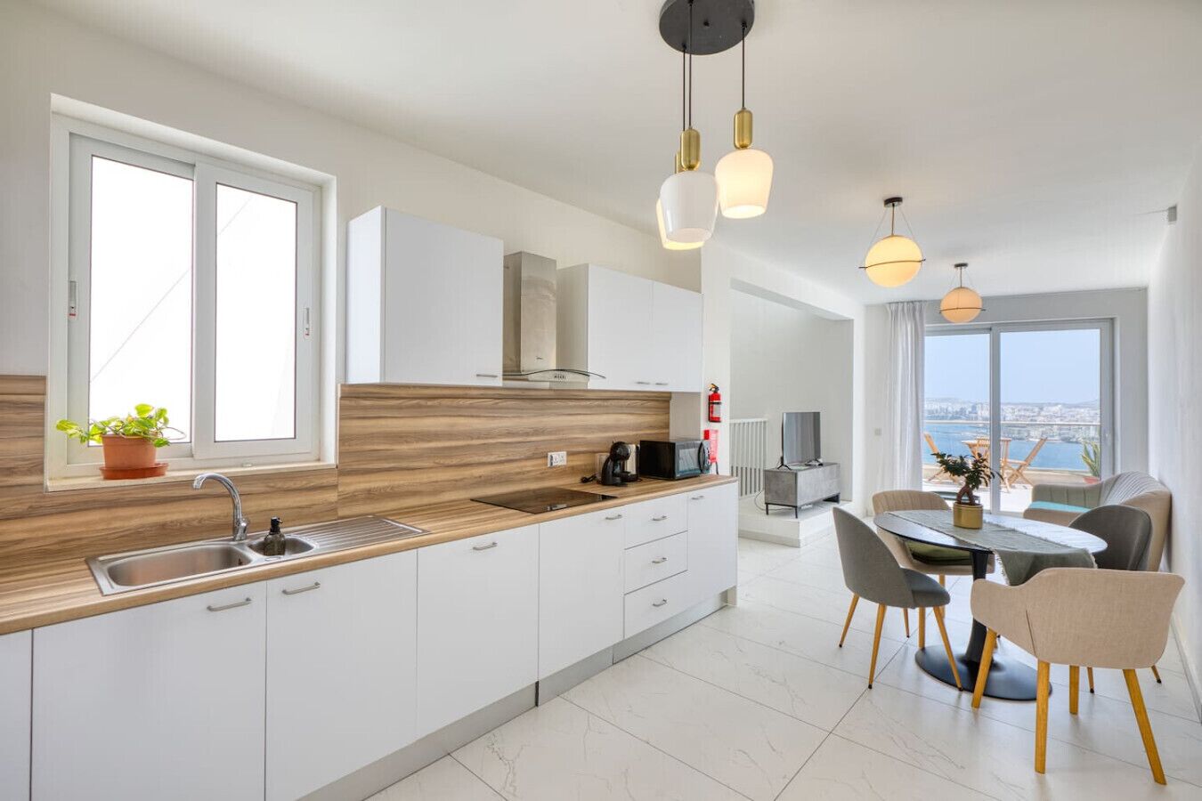 Une cuisine moderne avec un plan de travail en bois, des armoires blanches et un coin repas comprenant une table et des chaises.