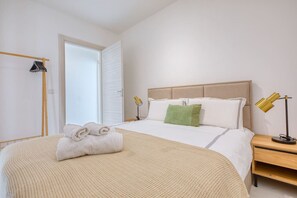 A hotel room with a bed, a bedside table, a lamp, and a wardrobe.