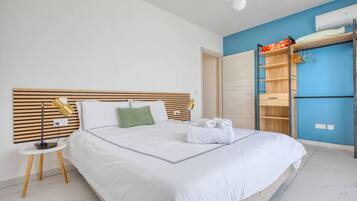 Une chambre d’hôtel moderne avec un grand lit, des tables de chevet, une armoire et un mur d’accent bleu.