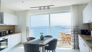 A modern kitchen with a dining area overlooking a body of water. - Blu Mar Sea View Appartment 4 (San Pawl il-Baħar)