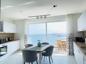 A modern kitchen with a dining area overlooking a body of water. - Blu Mar Sea View Appartment 4 (San Pawl il-Baħar)