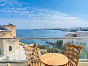 Ein Balkon mit Blick auf das Meer und die Stadtlandschaft.