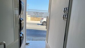 A hallway leading to a parking area with a clear view of a car and a building labeled 'Blin Mitz'. - Blu Mar Sea View Appartment 4 (San Pawl il-Baħar)