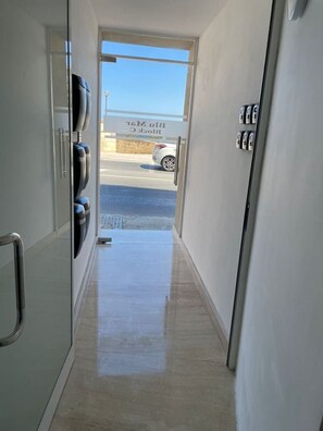 A hallway leading to a parking area with a clear view of a car and a building labeled 'Blin Mitz'. - Blu Mar Sea View Appartment 4 (San Pawl il-Baħar)