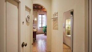 A hallway with a wooden floor, white walls, and a door with a round handle. - Bright Romantic Retreat in Florence (Firenze)