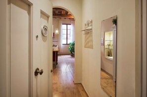 A hallway with a wooden floor, white walls, and a door with a round handle. - Bright Romantic Retreat in Florence (Firenze)