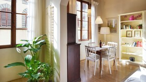 A dining area with a table and chairs, a bookshelf, and a potted plant. - Bright Romantic Retreat in Florence (Firenze)