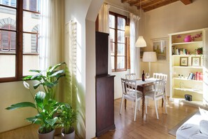 A dining area with a table and chairs, a bookshelf, and a potted plant. - Bright Romantic Retreat in Florence (Firenze)