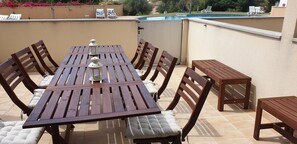 An outdoor patio with a wooden table and chairs, a pool in the background, and a view of the surrounding landscape. - Charming Holiday House With Stunning Views in Albufeira (Albufeira)