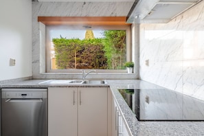 A modern kitchen with a built-in dishwasher, a stainless steel sink, and a window overlooking a garden. - Charming Holiday House With Stunning Views in Albufeira (Albufeira)