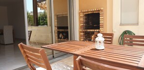 A wooden table with chairs, a white lantern, and a brick fireplace. - Charming Holiday House With Stunning Views in Albufeira (Albufeira)